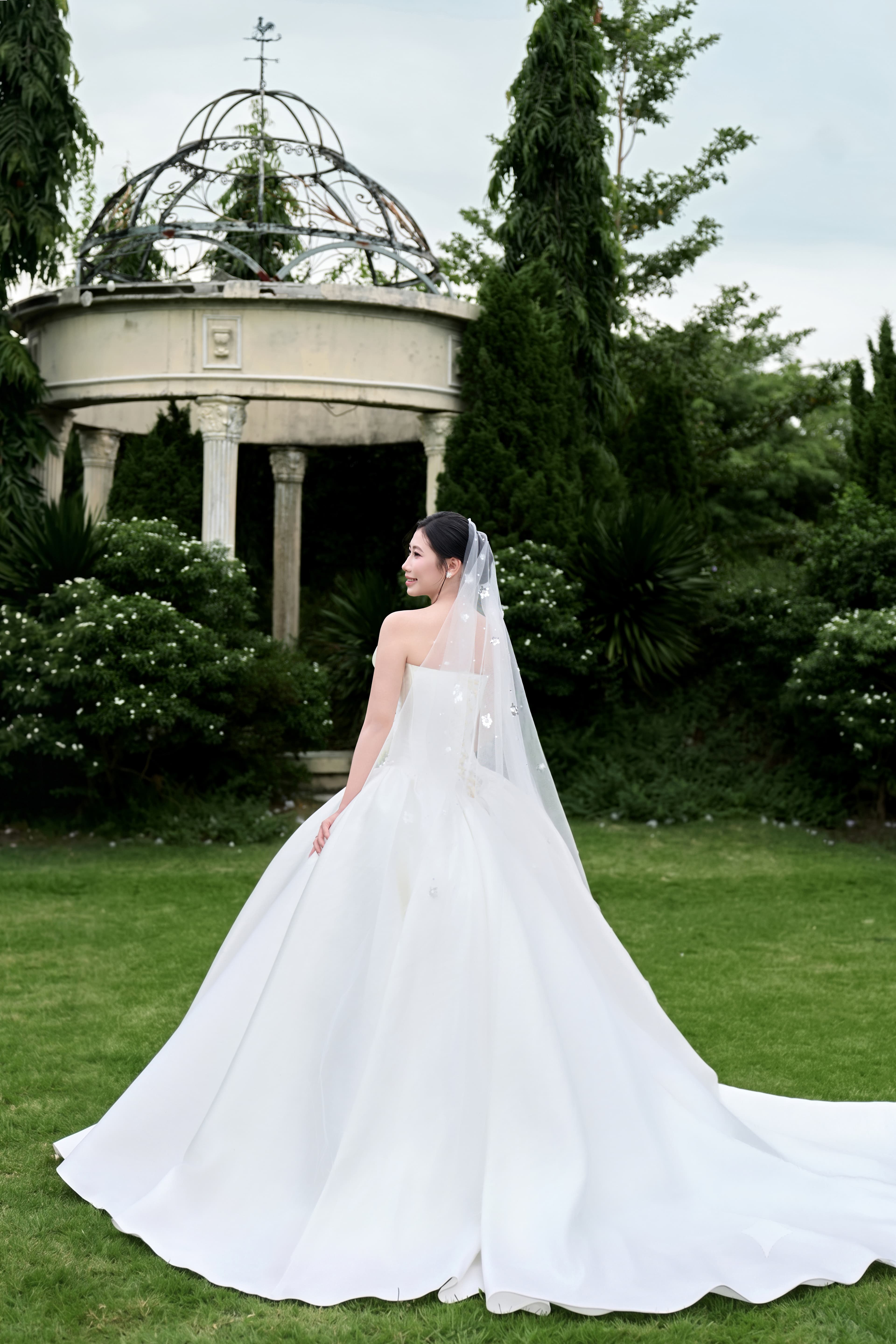 Cô dâu Ngọc Huyền kiều diễm trong tà váy cưới trắng tinh khôi, mỉm cười rạng rỡ giữa không gian khu vườn cổ tích